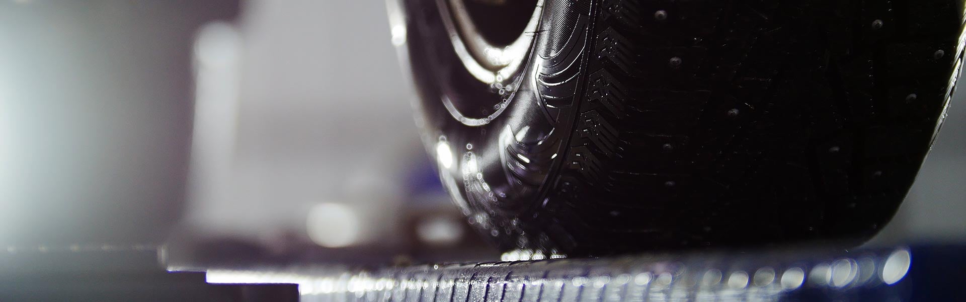A close-up shot of a car tire resting on a vehicle lift during routine service inspection.